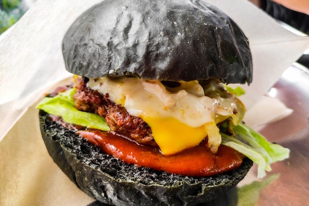 Burger mit schwarzer Brötchennahaufnahme. Appetitliches Streetfood.