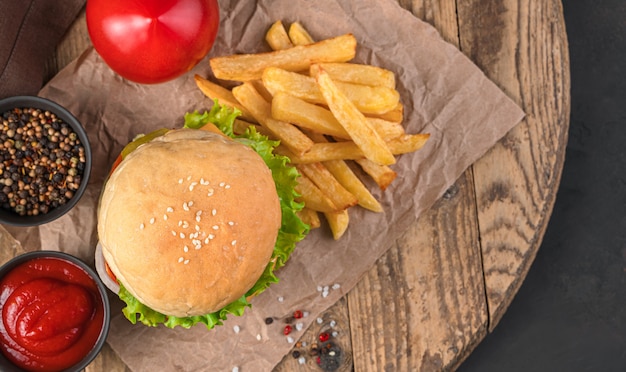 Burger, Pommes Frites und Soße auf einem Holzbrett. Ansicht von oben. Fastfood.