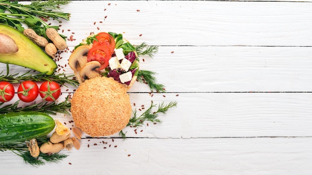 Burger, Sandwich mit Schafskäse, Pilzen und Salatblättern. Auf einem hölzernen Hintergrund. Ansicht von oben. Platz kopieren.