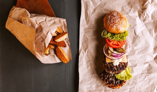 Burger se decompôs em seus componentes em papel kraft em uma mesa de madeira. pacote de batatas fritas.