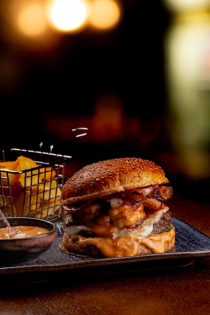 Foto burger surf and turf com burger mit geschmolzenem rindfleisch, cheddar-garnelen und cheddar-sauce, fetter schwarzer hintergrund