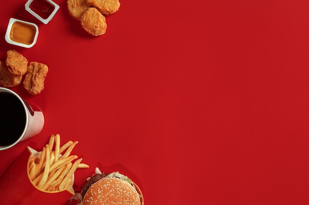 Burger und Pommes Frites Hamburger und Pommes frites in roter Pappschachtel Fast Food auf rotem Hintergrund