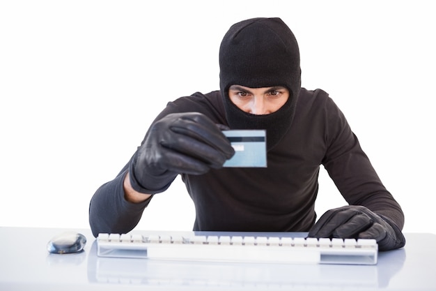 Burglar fazendo compras on-line com laptop e cartão de crédito