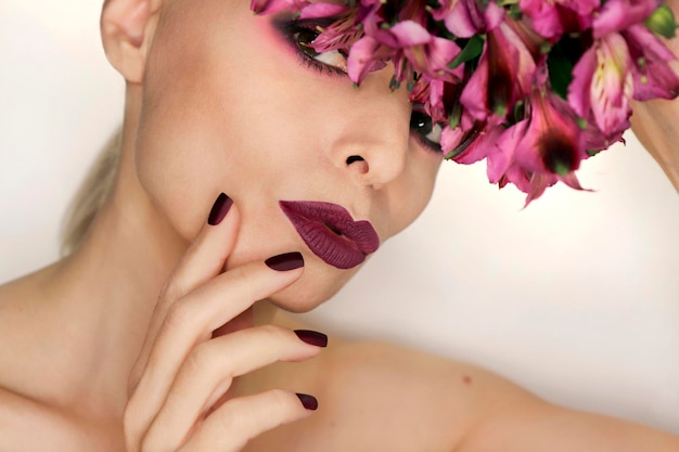 Burgunder Maniküre und Make-up auf einem Mädchen mit Blumen