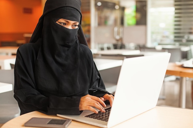 Burka bekleidete afghanische Frau, die am Laptop arbeitet