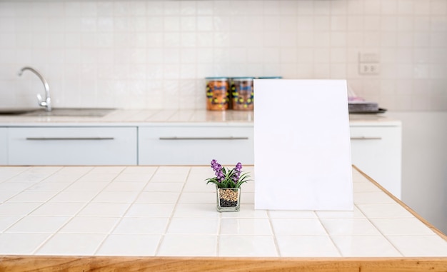 Burlarse del marco del menú en blanco y la planta de interior con copia espacio en la mesa en la sala de cocina