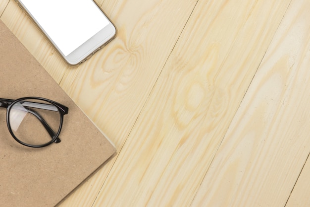 Burlarse de la pantalla en blanco en el teléfono móvil y eyeglassse en libreta marrón