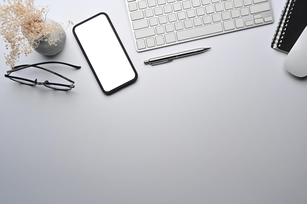 Burlarse de un teléfono móvil con pantalla en blanco en una mesa blanca.