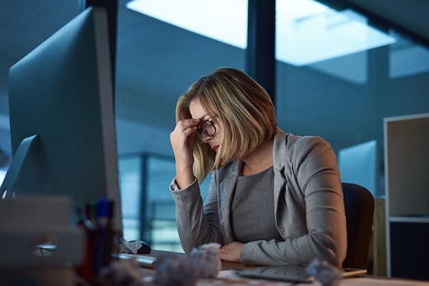 Foto burnout de dor de cabeça e mulher de negócios no escritório cansada ou fadiga enquanto trabalhava tarde da noite no computador enxaqueca de estresse e pessoa do sexo feminino com ansiedade de depressão ou nevoeiro cerebral doente e prazo