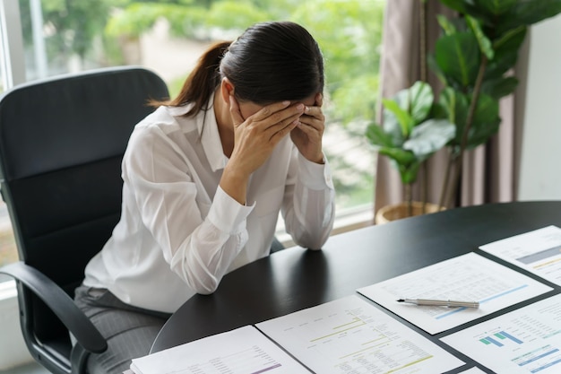 Burnout-Konzept Asiatische Geschäftsfrau berührt die Stirn, hat Kopfschmerzen, langweiligen Job und müde emotionale Schmerzen und eine professionelle Person, die wegen des Risikos deprimiert ist