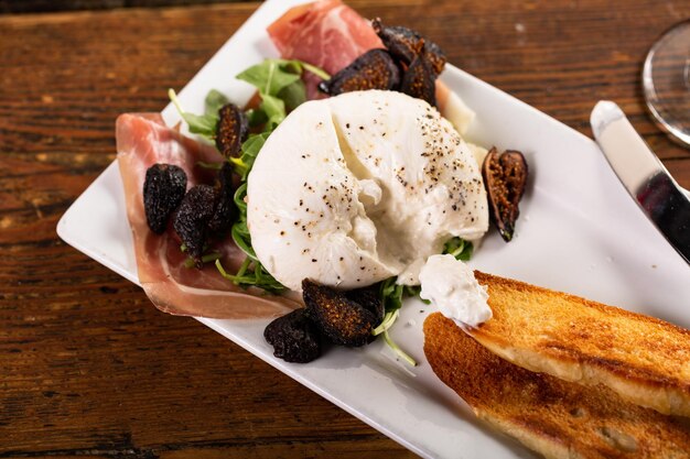 Burrata aperitivo con prosciutto higos secos y pan tostado