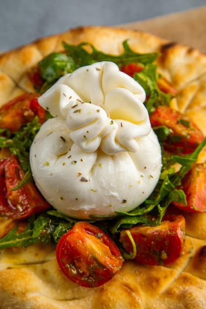 Burrata Caprese Salat mit Spinat mit Burrata Caprese Kirschtomaten und schwarzem Hintergrund