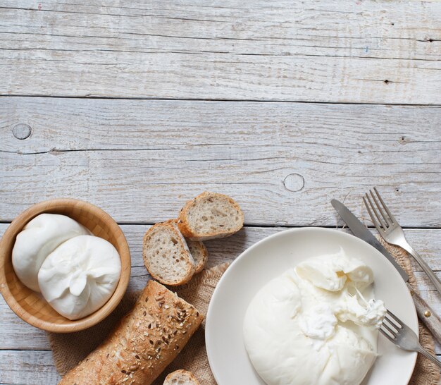 Burrata de queijo italiano com pão na superfície de madeira