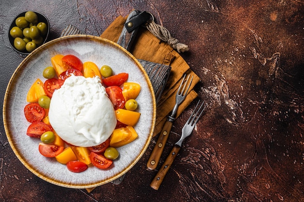 Burrata-Käse und Tomatensalat serviert auf rustikalem Teller Dunkler Hintergrund Draufsicht Kopierbereich