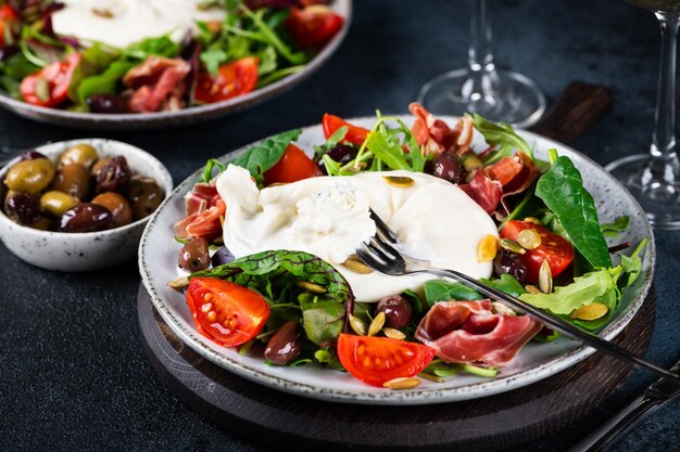 Foto burrata, queso fresco italiano elaborado con nata y leche de búfala o vaca. ensalada de burrata con tomates y mix de ensaladas. concepto de alimentación saludable. ensalada de dieta cetogénica.