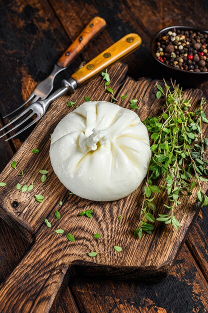 Burrata de queso fresco italiano sobre una tabla para cortar madera