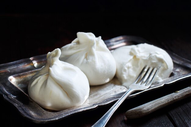 Burrata de queso italiano con tenedor sobre un fondo oscuro