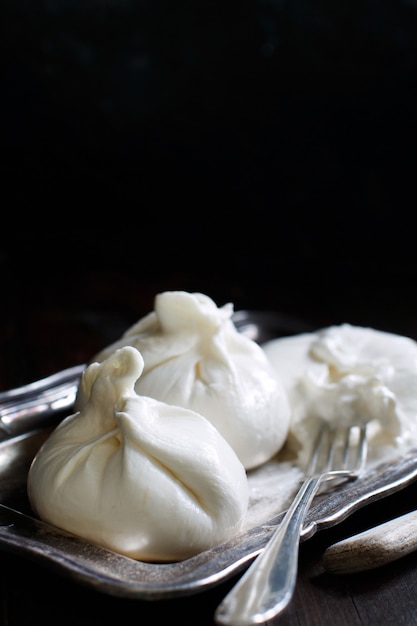 Burrata de queso italiano con tenedor sobre un fondo oscuro