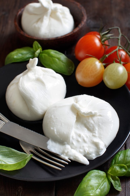 Foto burrata de queso italiano con tomates y hierbas