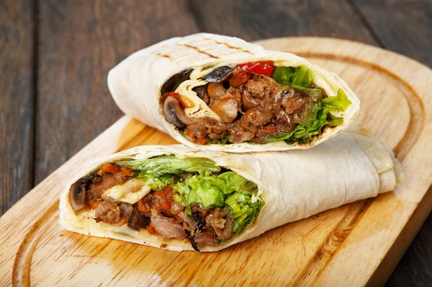 Burrito com carne de porco e legumes na mesa de madeira