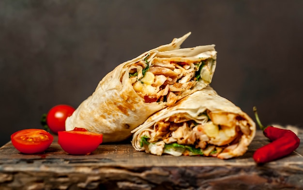 Foto burrito envolve com frango e legumes em uma tábua, contra um fundo de concreto, shawarma mexicano