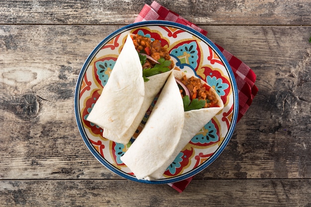 Burrito mexicano típico wrap com carne, frijoles e legumes na mesa de madeira