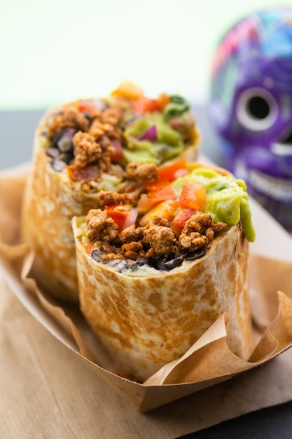 Foto burrito mit hackfleisch und salsa und guacamole in einem fastfood-straßencafé mit einem totenkopf im hintergrund