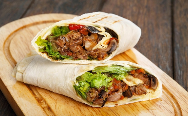 Burrito mit Schweinefleisch und Gemüse an einem Holzschreibtisch
