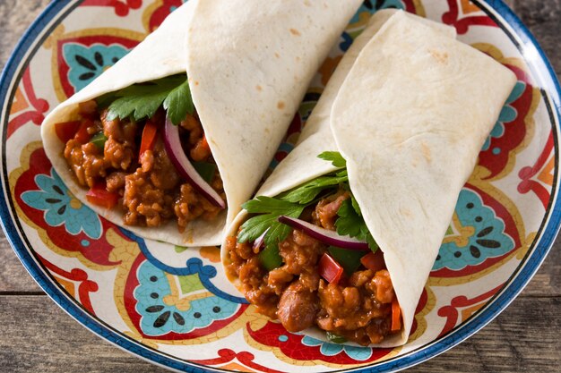 Burrito típico mexicano envuelto con carne de res, frijoles y verduras en la mesa de madera