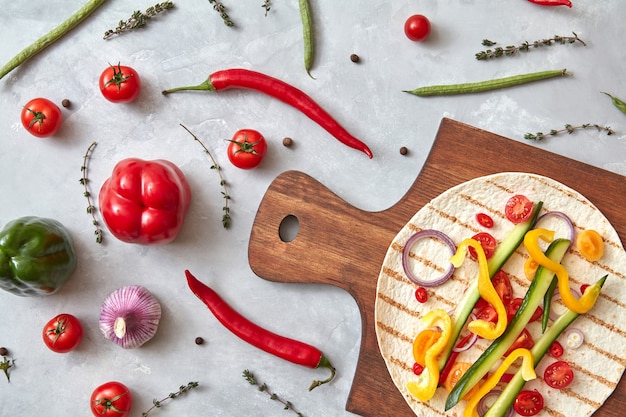 Burrito de verduras en un plato y sobre una tabla de madera