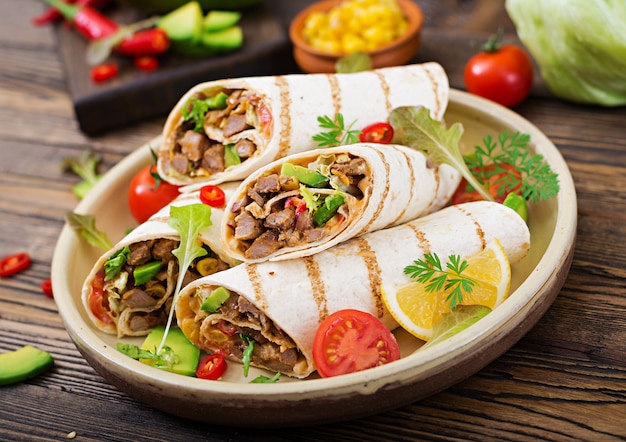 Burritos envolve com carne e legumes em uma mesa de madeira. Burrito de carne, comida mexicana. Cozinha mexicana.