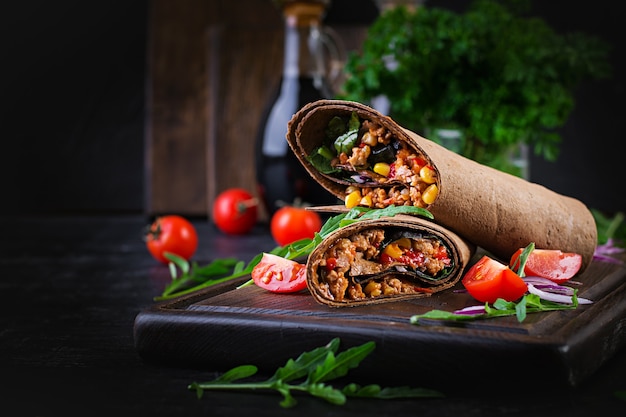 Burritos envolve com carne e legumes no fundo escuro de madeira. Burrito de carne, comida mexicana.