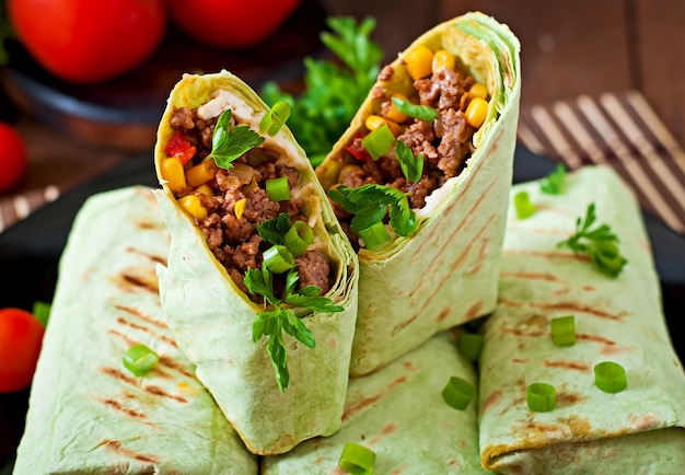 Burritos envolve com carne picada e legumes em uma superfície de madeira