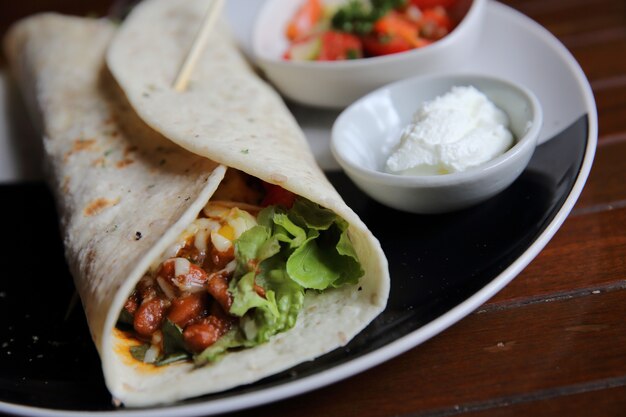 Burritos mexicanos en un plato con ensalada de tomate