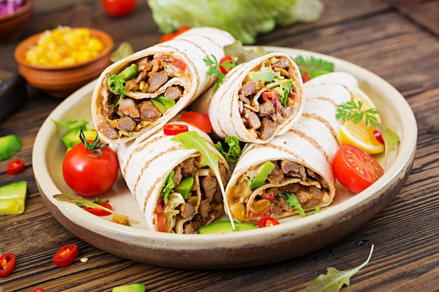 Burritos wickelt mit Rindfleisch und Gemüse auf einem Holztisch ein. Rindfleisch Burrito, mexikanisches Essen. Mexikanische Küche.