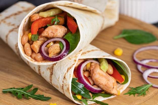 Burritos wraps com frango e legumes em fundo escuro. comida mexicana.