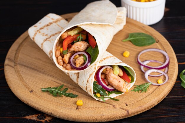 Burritos wraps com frango e legumes em fundo escuro. Comida mexicana.