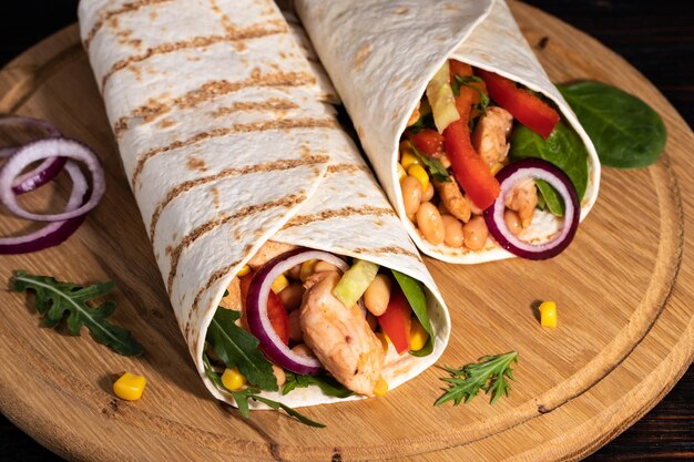 Burritos wraps com frango e legumes em fundo escuro. Comida mexicana.