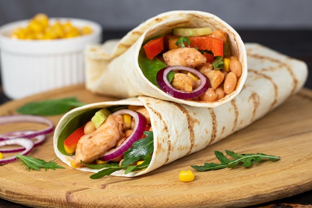 Burritos Wraps mit Huhn und Gemüse auf dunklem Hintergrund. Mexikanische Nahrung.