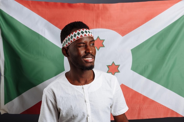 Burundi-Flagge hinter dem lustigen Mann, der lächelt und lacht und Gesten wie eine Hand zeigt