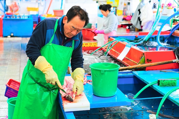 Busan, Coreia do Sul - 13 de março de 2016: Vendedor cortando peixe no mercado em Jagalchi em Busan, Coreia do Sul