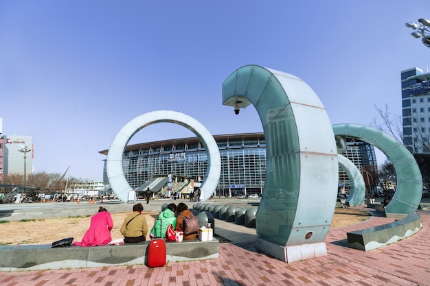 Foto busan, südkorea - 12. märz 2016: touristen mit ihrem gepäck sitzen in der nähe des bahnhofsgebäudes in busan, südkorea