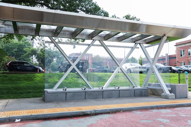 Busbahnhofszene mit verschiedenen Pendlern, die unter einem Stahldach warten. Sonnenlicht dringt durch Cre