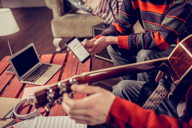 Buscando melodía. Cerca de dos músicos en busca de alguna melodía en Internet mientras toca la guitarra