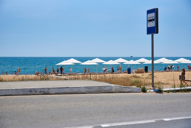 Bushaltestelle mit einem Schild am Meerstrand.