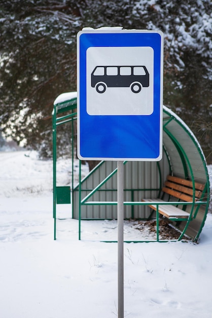 Bushaltestelle mitten in einer schönen Winterstraße mitten im Wald mit Bushaltestellenschild