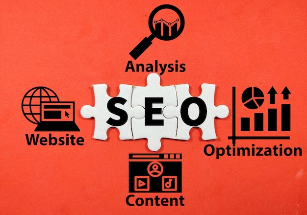 Business Education conceptText SEO Search Engine Optimization mit Puzzle und einfachem Symbol auf rotem Hintergrund