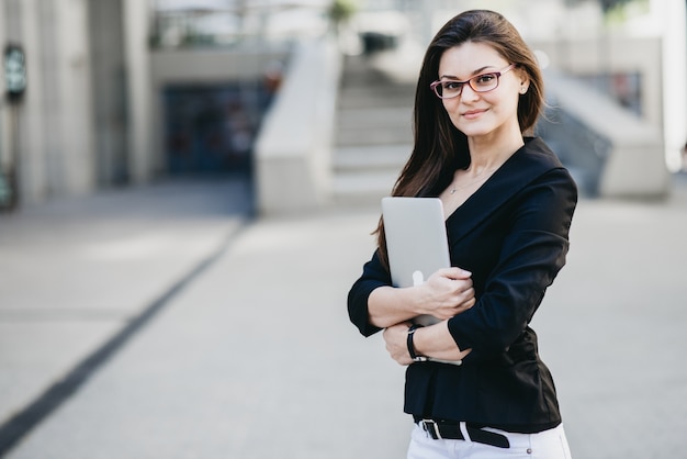 Business-Frau mit einem Laptop auf einer Straße in einer modernen Stadt