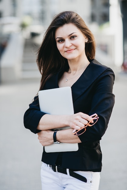 Business-Frau mit einem Laptop auf einer Straße in einer modernen Stadt