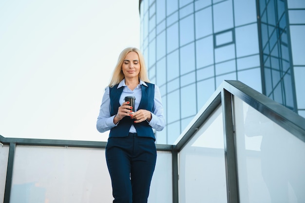 Business-Frau mit Telefon in der Nähe von Büro Porträt der schönen lächelnden Frau in modischer Bürokleidung, die am Telefon spricht, während sie im Freien steht Telefonkommunikation Hochwertiges Bild